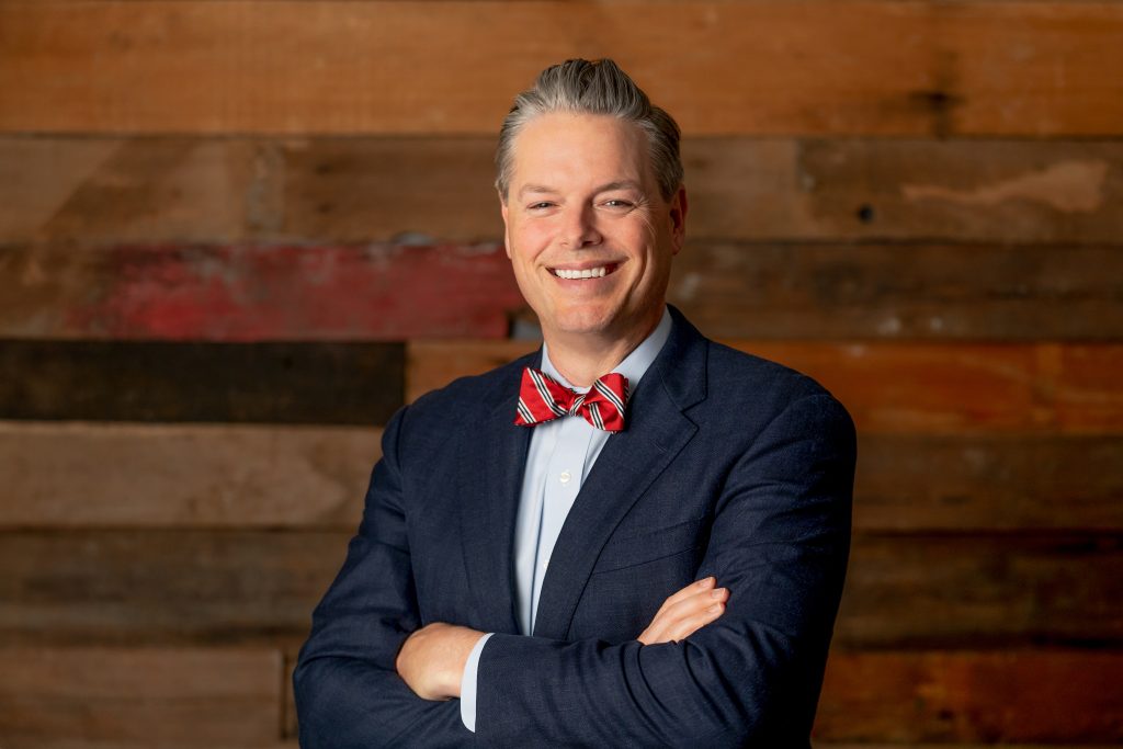 man standing in front of wooden wall with arms crossed