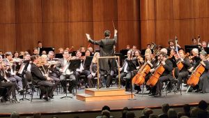 man stands in front of symphony conducting