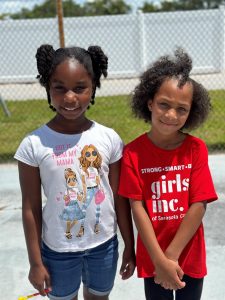 two young girls smile at the camera outside
