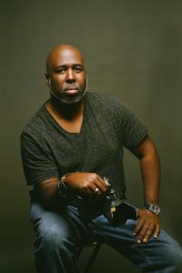man sits on a stool with a camera in his hand