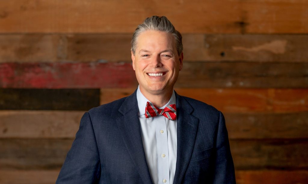man standing in front of wooden wall smiling