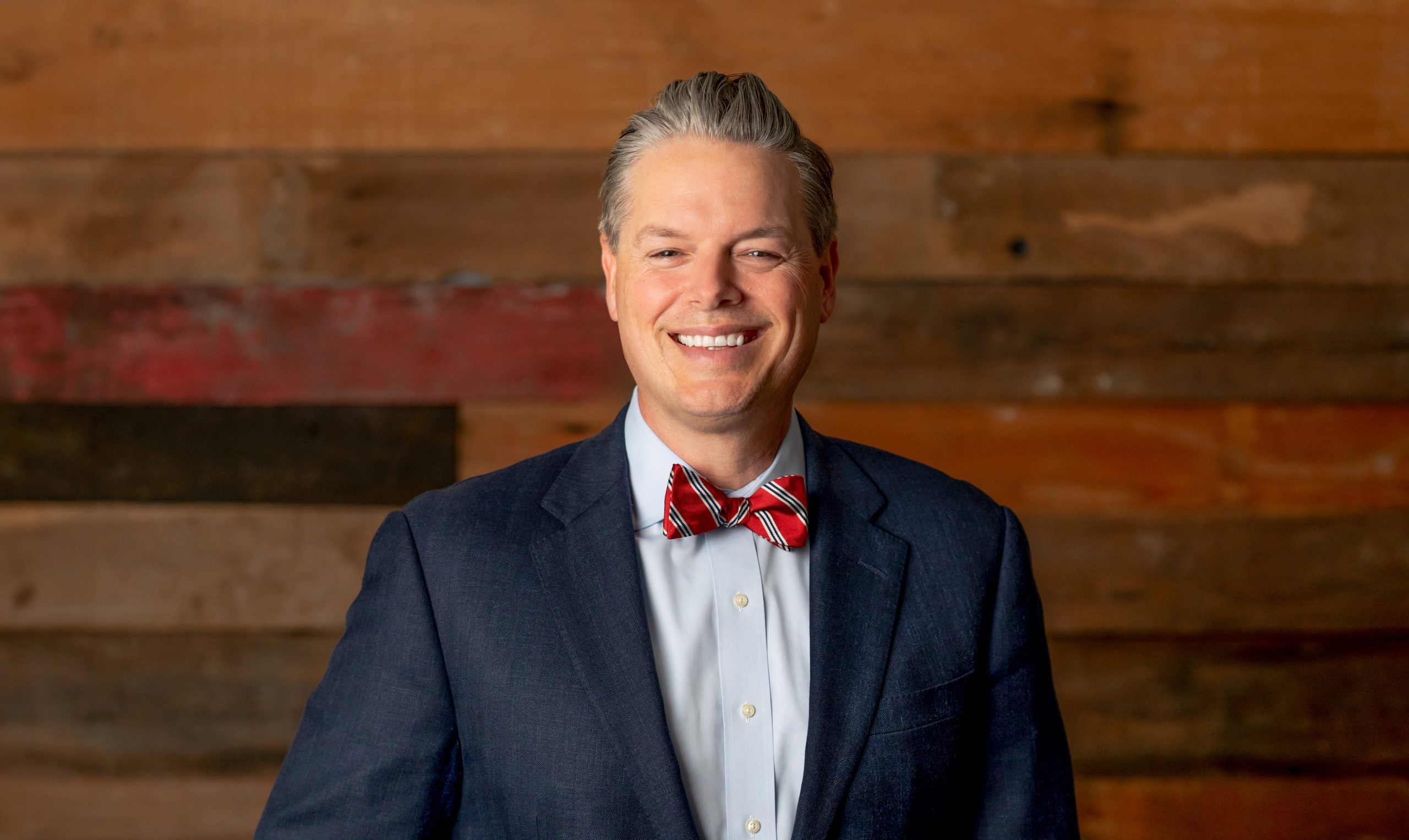 man standing in front of wooden wall smiling